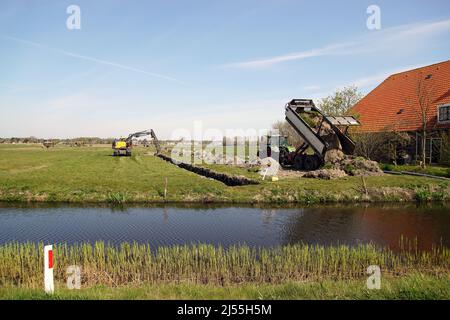 Pelle hydraulique hollandaise creusant un fossé dans un pré et une ractereuse avec une remorque avec le sol. Printemps, avril, pays-Bas Banque D'Images