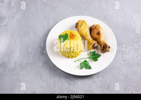 riz au curcuma et cuisses de poulet cuites sur plaque blanche sur fond gris Banque D'Images
