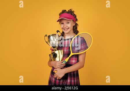 le succès sportif. une jeune fille heureuse de vêtements de sport a remporté le prix. coupe de championnat. une raquette de badminton réussie pour enfant. un joueur de tennis pour enfant est champion. h Banque D'Images