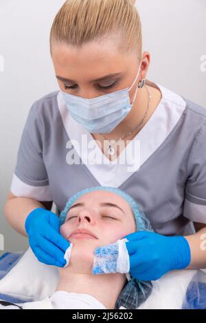 Le cosmétologue traite la peau du visage avec un tonique afin d'hydrater et de nettoyer la peau avant les procédures cosmétiques Banque D'Images