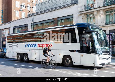 Un cycliste passe un autocar National Express à Oxford Street, Londres, Royaume-Uni passe un autocar National Express à Oxford Street, Londres, Royaume-Uni Banque D'Images