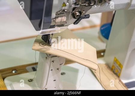 Aiguille de machine à coudre industrielle et morceau de cuir avec coutures en gros plan Banque D'Images