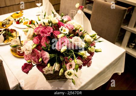 Un bouquet de mariage d'eustomas multicolores sur une table recouverte d'une nappe blanche. Banque D'Images