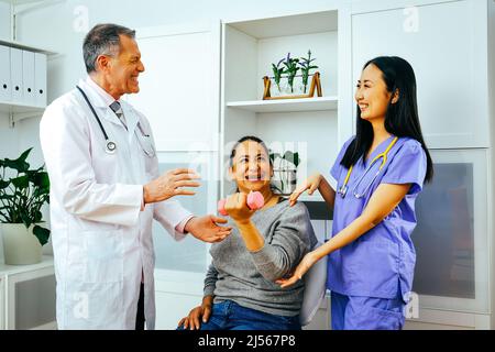 sourire médecin de réadaptation physiothérapeute médecin et infirmière praticien aidant le patient lever la haltère d'une main. Clinique de l'industrie de la santé Banque D'Images