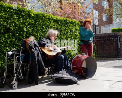 Elderdly homme et femmes avec un fauteuil roulant sur Portabello Road, jouant la guitare, la batterie et l'harmonica. Londres. Banque D'Images