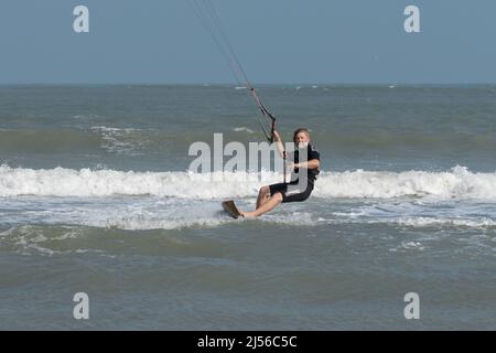 Un surfeur cerf-volant sur une planche de surf en bois coupe les vagues tout en piquant dans le golfe du Mexique à South Padre Island, Texas. Banque D'Images