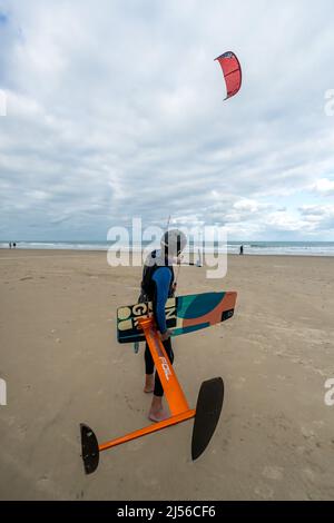 Un ancien surfeur kite lance son kite à un jour de tempête sur la plage de South Padre Island, Texas. Il porte son hydroptère. Banque D'Images