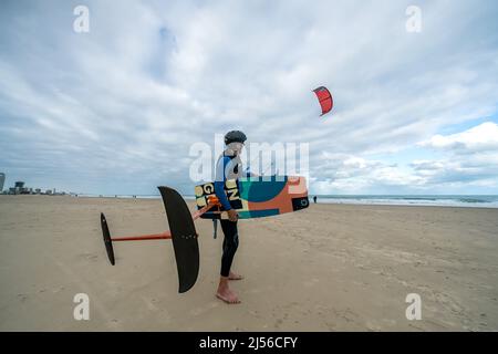 Un ancien surfeur kite lance son kite à un jour de tempête sur la plage de South Padre Island, Texas. Il porte son hydroptère. Banque D'Images