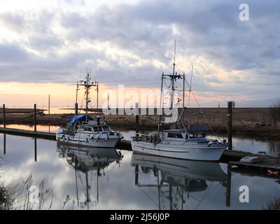 Bateaux sur un coucher de soleil d'hiver par jour nuageux Banque D'Images