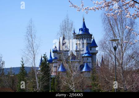 Château bleu vintage dans les arbres au parc lors d'une journée ensoleillée de printemps avec des fleurs en fleurs Banque D'Images