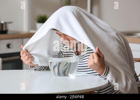 Jeune homme qui fait l'inhalation de vapeur à la maison pour apaiser et ouvrir les passages nasaux Banque D'Images