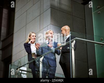 Les gens de l'entreprise multinationale et multiethnique de discuter affaires using digital tablet in modern office building, low angle view. Banque D'Images