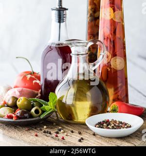 Un arrangement d'huile et de vinaigre de vin rouge avec des olives et des grains de poivre Banque D'Images