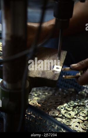 Production de pièces de monnaie balinaises traditionnelles avec creux connu sous le nom de 'pis bolong/jinah bolong/uang kepeng' dans le village de Kamasan, Klungkung, Bali, Indonésie. Utilisées dans les transactions à travers Bali dans le passé, les pièces sont aujourd'hui essentielles dans les rituels religieux traditionnels de l'île des dieux. Banque D'Images