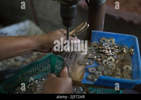 Production de pièces de monnaie balinaises traditionnelles avec creux connu sous le nom de 'pis bolong/jinah bolong/uang kepeng' dans le village de Kamasan, Klungkung, Bali, Indonésie. Utilisées dans les transactions à travers Bali dans le passé, les pièces sont aujourd'hui essentielles dans les rituels religieux traditionnels de l'île des dieux. Banque D'Images