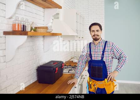Portrait d'un jeune plombier ou réparateur heureux pendant les travaux d'entretien dans la cuisine Banque D'Images