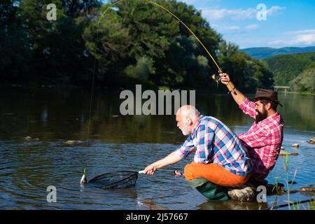 Pêcheurs hommes amis et truite trophée. Père et fils de pêche. Générations hommes pêche dans la rivière. Banque D'Images