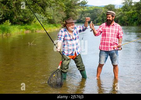 Pêcheurs hommes amis et truite trophée. Père et fils de pêche. Générations hommes pêche dans la rivière. Heureux heureux heureux heureux heureux heureux homme amis. Banque D'Images