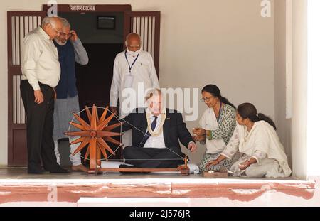 Le Premier ministre Boris Johnson montre comment faire fonctionner une roue en coton dans la maison de Mahatma Gandhi à l'Ashram Sabarmati à Ahmedabad lors d'une visite culturelle dans le cadre de sa visite de deux jours en Inde. Date de la photo : jeudi 21 avril 2022. Banque D'Images