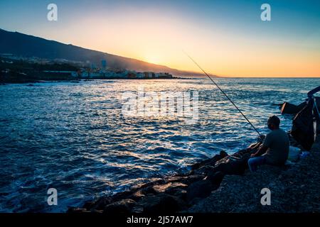 Pêche au large de l'Atardecer au coucher du soleil sur Playa jardin dans la ville de Puerto de la Cruz dans le nord des îles Canaries de Ténérife Banque D'Images