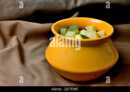 Morceaux de mangue crus dans un bol jaune sur fond marron Banque D'Images