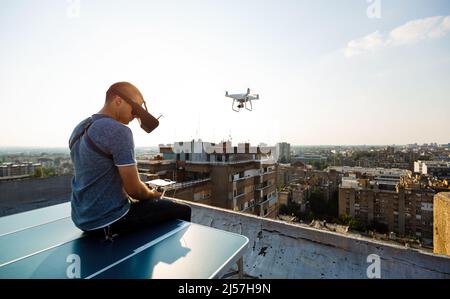 Jeune technicien homme volant UAV drone avec télécommande dans la ville Banque D'Images