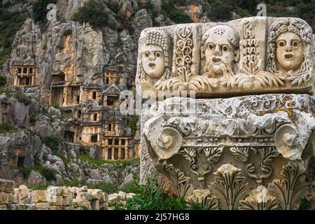 Visages et masques de théâtre en pierre dans la ville antique de Myra. Tombeaux de roche lycienne en arrière-plan. Demre, Antalya Banque D'Images