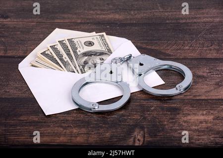 menottes allongées sur une enveloppe blanche ouverte avec des dollars, gros plan sur un fond sombre Banque D'Images