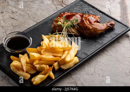 Carcasse de caille grillée avec frites sur plaque sur fond de pierre noire. Cailles rôties sur l'assiette. Vue de dessus, plan d'appartement. Banque D'Images