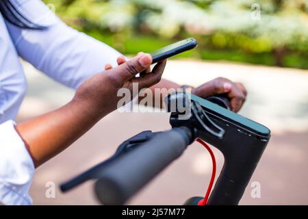 afro-américaine femme activer et payer à l'avance un e-scooter de location ou un e-vélo dans la rue Banque D'Images