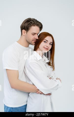 Jeune homme embrassant souriant redhead petite amie isolée sur blanc Banque D'Images