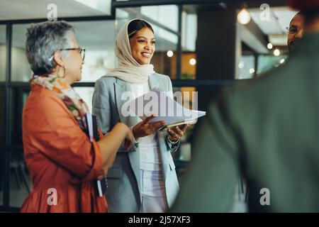 Des hommes d'affaires joyeux souriant lors d'une réunion du personnel dans un bureau moderne. Groupe de professionnels d'affaires prospères travaillant en équipe en un m Banque D'Images