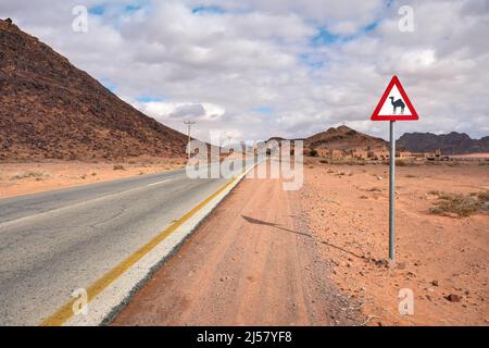 Route désertique vide à Wadi Rum, triangle rouge avertissement Camels près. Banque D'Images