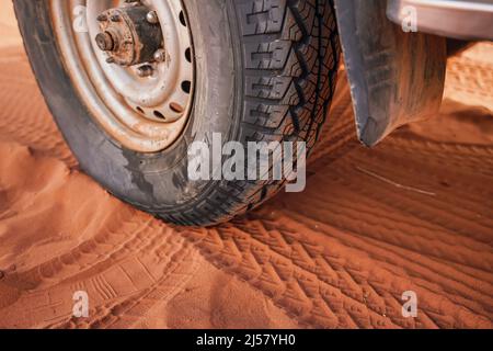 pneu de véhicule 4wd, sale de la poussière - impression de piste visible dans le sable rouge, détail de gros plan. Banque D'Images