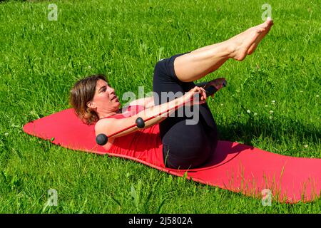 Femme faisant des exercices pilates avec barre vibrante Banque D'Images