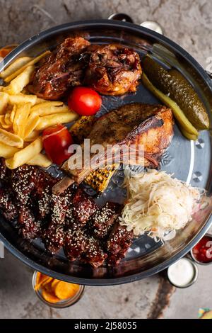 Assiette de viandes délicieuses, côtes de porc, poulet grillé, saucisse, bœuf, Pommes de terre grillées. Sauce délicieux assortiment de viandes grillées aux légumes et aux herbes Banque D'Images