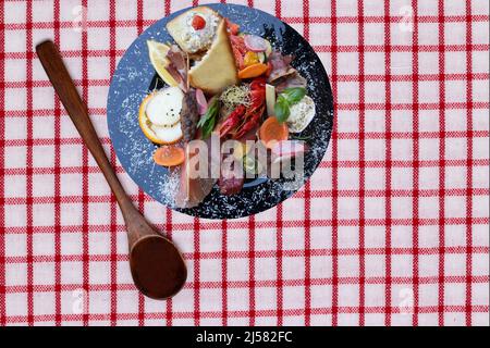 Cuisine traditionnelle italien. Gros plan de hors-d'œuvre méditerranéens ou d'antipasti et de tapas avec des légumes au jambon et du cancer sur une assiette noire et une cuillère Banque D'Images