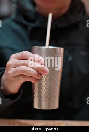 Homme tenant une tasse de métal avec du thé au lait, du thé au lait de style Hong Kong Banque D'Images