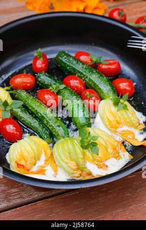 Cuisine du sud de l'Allemagne, fleurs de courgettes farcies sautées dans une poêle, fromage à la crème, tomates cocktail, tomates cerises, végétarienne, une cuisine saine Banque D'Images