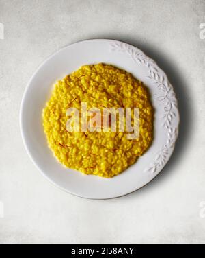 Risotto alla milanais habillé de fils de safran et d'un fromage Parmigiano Reggiano. Banque D'Images