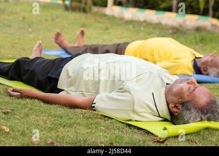 Photo complète des vieux hommes pratiquant Shavasana ou corps pose à la fin d'un cours - concept de yoga pour les personnes âgées, vie active et saine pour les personnes âgées Banque D'Images