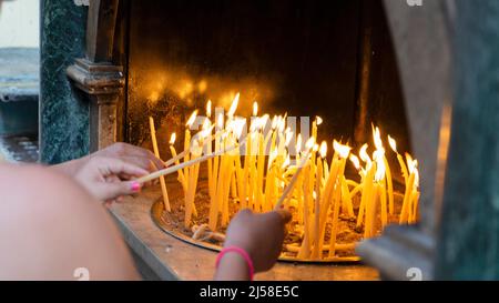 Les gens allument des bougies à l'extérieur d'une église orthodoxe sur l'île de Corfou en Grèce Banque D'Images