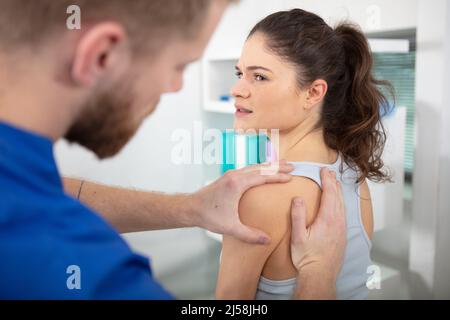 physiothérapeute femme professionnelle donnant un massage d'épaule à une femme brune Banque D'Images
