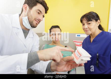 Dentist showing patient modèle à mâchoires dans une clinique dentaire Banque D'Images