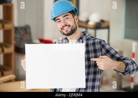 joyeux homme de construction tenant une bannière blanche Banque D'Images