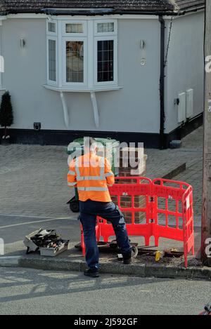 Un ingénieur de communication BT OpenREACH travaillant sur un boîtier de ligne téléphonique dans une rue de banlieue Surrey Angleterre Royaume-Uni Banque D'Images