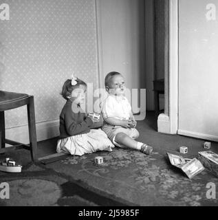 1962, historique, petits enfants, frère et sœur jouant des blocs de lettres en bois dans une salle de devant, Angleterre, Royaume-Uni. Banque D'Images