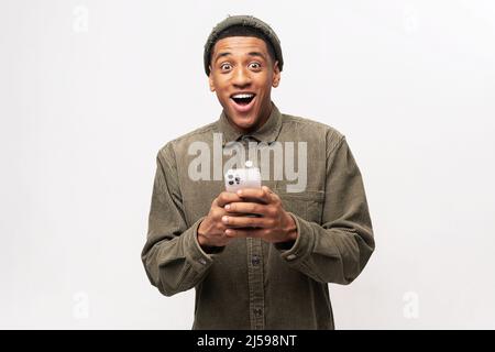 Drôle surpris gars branché soudainement lire le message sur son téléphone mobile et exprimant l'étonnement de choc, des nouvelles incroyables sur smartphone.Studio tourné isolé Banque D'Images