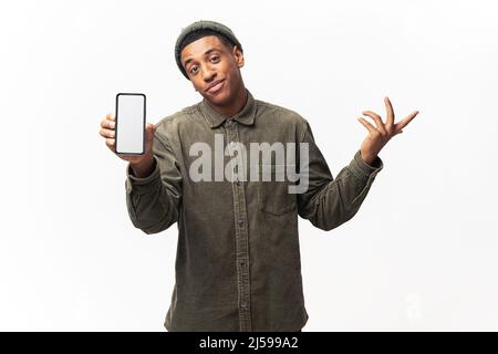 Portrait d'un homme attrayant portant une chemise décontractée tenant un smartphone entre les mains, écartant hans, ne sais pas comment utiliser l'application. Studio d'intérieur isolé sur fond blanc Banque D'Images