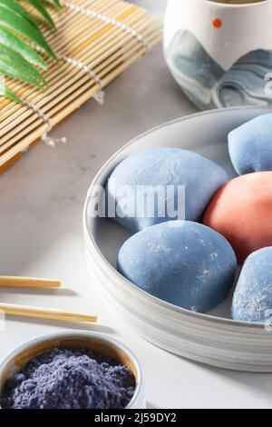 Concept d'un dessert japonais traditionnel. Un bol en céramique de mochi japonais avec baguettes et maki sudare mat sur comptoir blanc. Gâteau de riz asiatique Banque D'Images